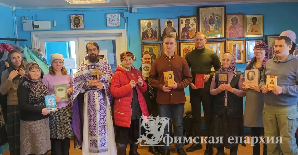 Настоятель с группой прихожан держат в руках православные книги в приходском помещении